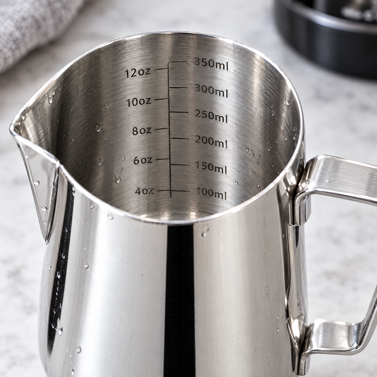 Milk frothing jug pointed spout and interior measurement markings close-up
